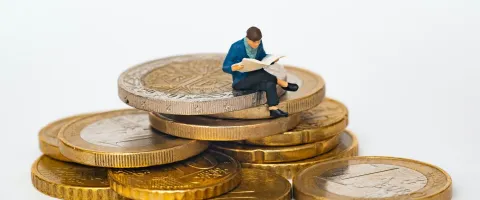 Man sitting on coins reading