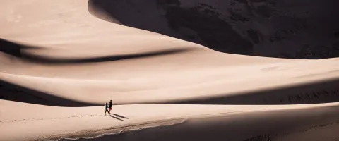 Two People Walking Through the Desert