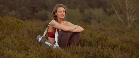 Frau nachdenklich mit Yogamatte