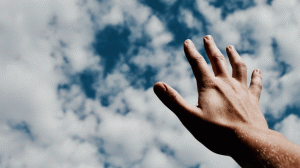 Hand greift zum Himmel