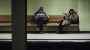 Zwei Männer lesen an der Ubahn-Haltestelle