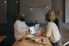 Drei Menschen sitzen mit Masken um einen Tisch