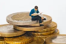 Man sitting on coins reading