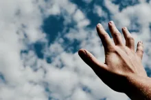 Hand greift zum Himmel