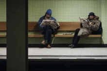 Zwei Männer lesen an der Ubahn-Haltestelle